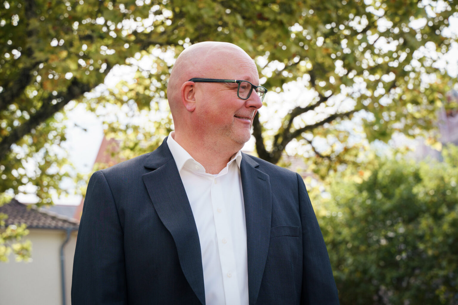 Seitliches Porträt eines Wirtschaftsprüfers der Emsland Audit GmbH Wirtschaftsprüfungsgesellschaft im Anzug im Außenbereich mit Bäumen
